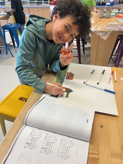 A young student sketches the building he will construct with building blocks.