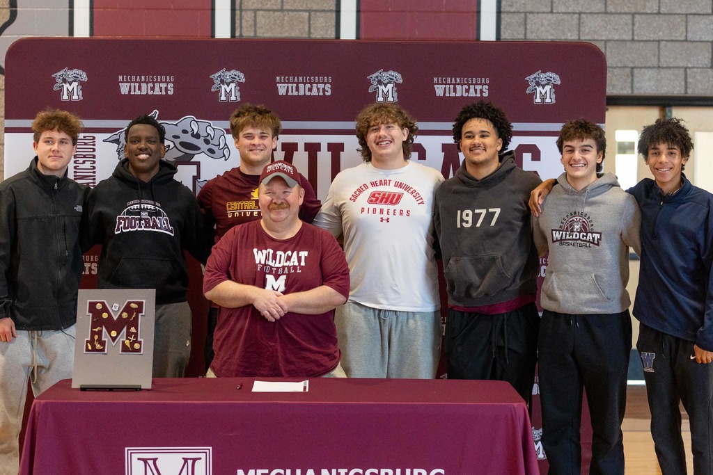 Group of football players standing in front of a table.