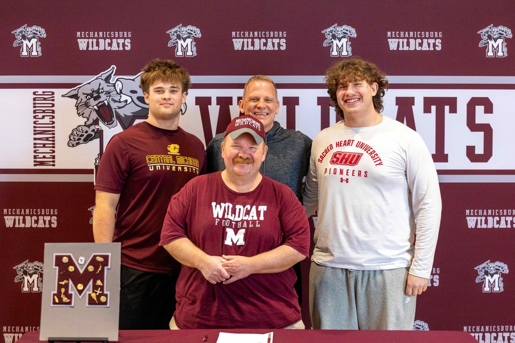 Group of football players standing in front of a table.