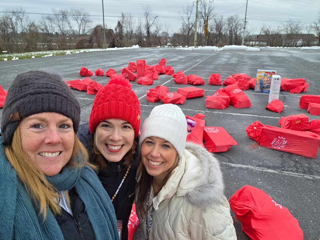 Ladies surrounded by lots of red bags full of gifts.