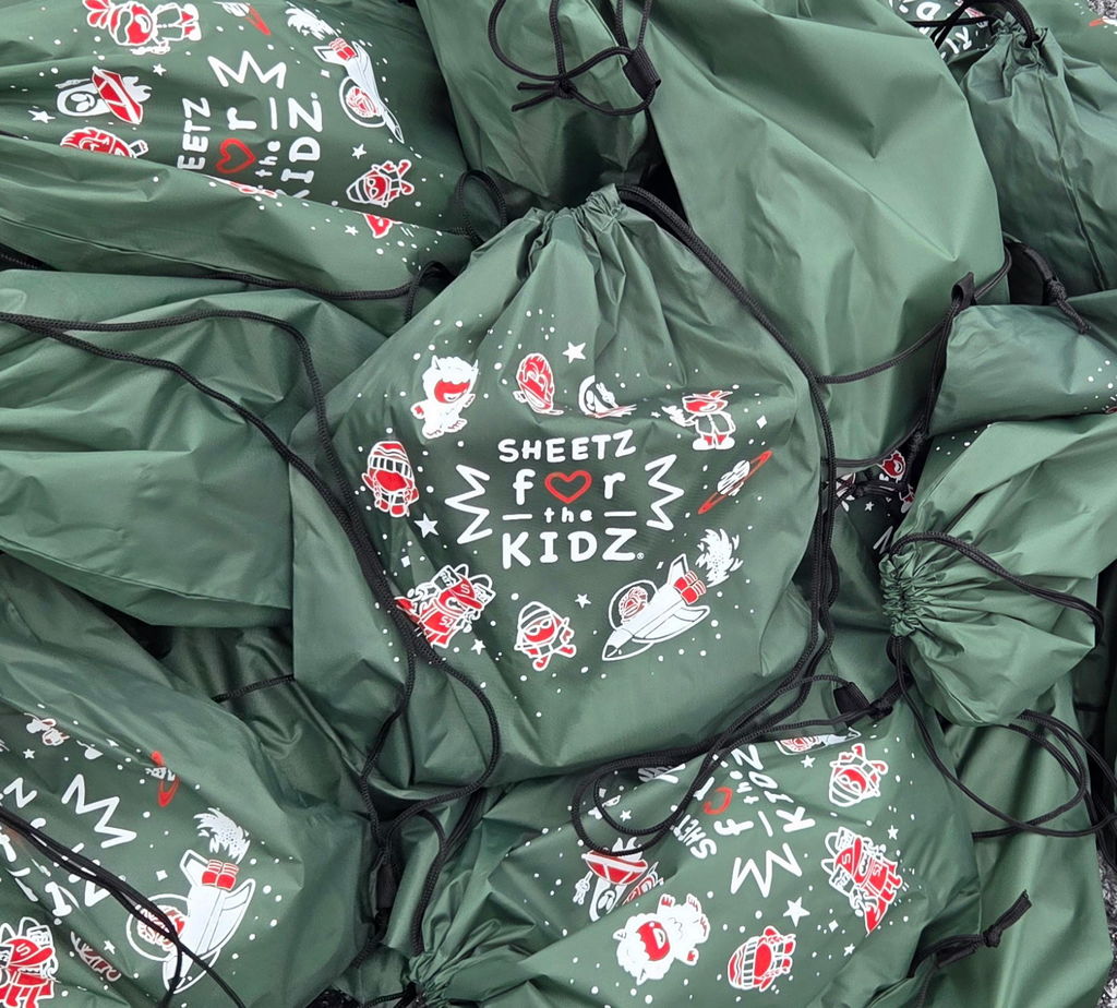 A pile of green bags full of holiday gifts.