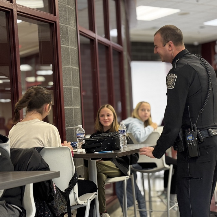 a police officer talks to students at a lunch table  