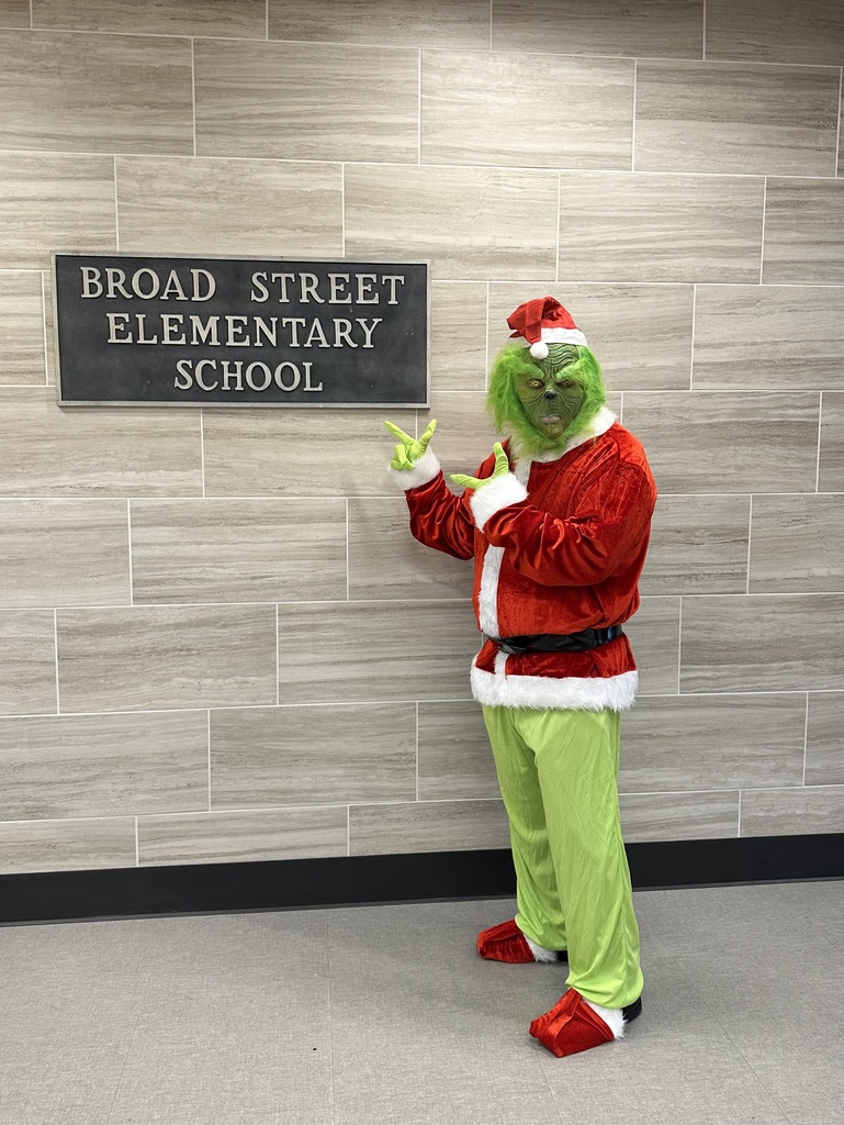 The grinch pointing to a sign that says Broad Street Elementary School.