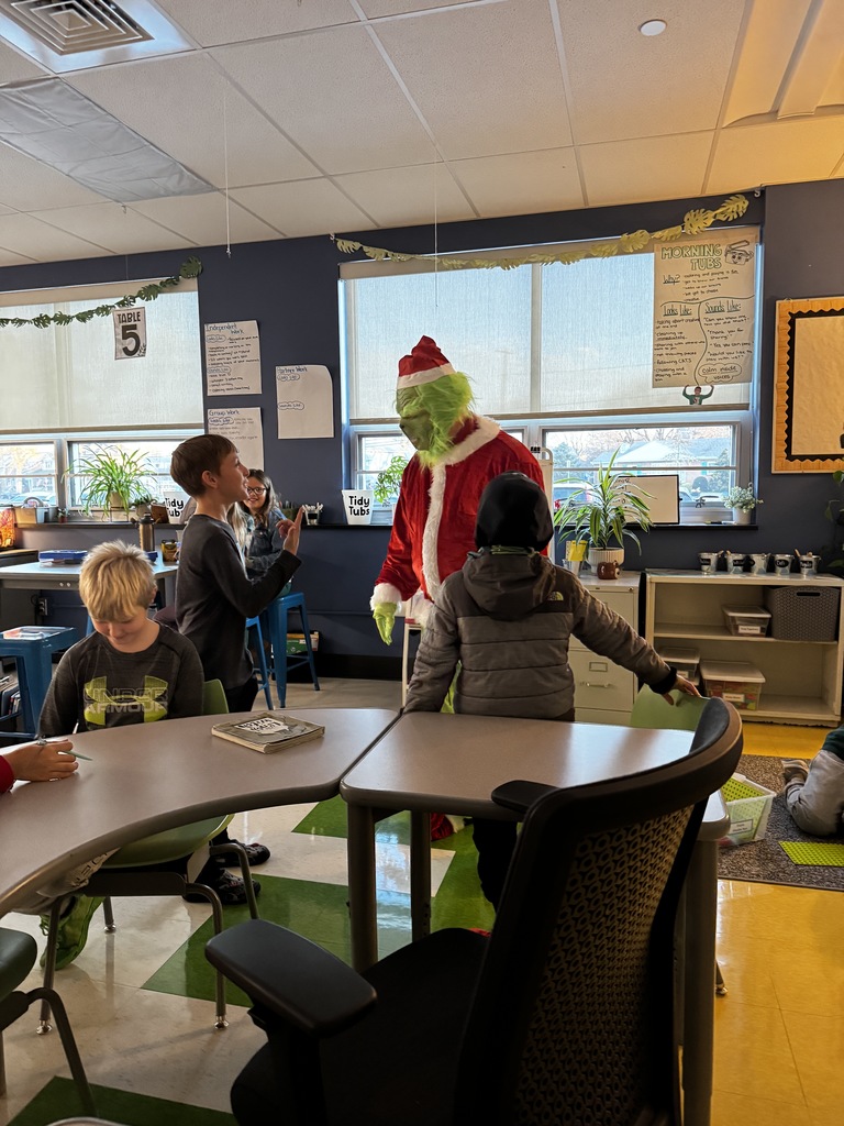The Grinch talking to students in a classroom.