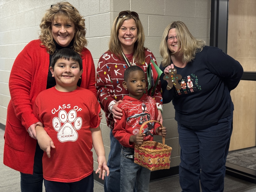 Two young students deliver handmade gingerbread men to staff in an office.