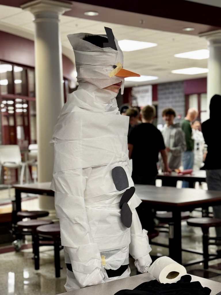 Students wrapping a classmate in toilet paper for a Build A Snowman STEM challenge.