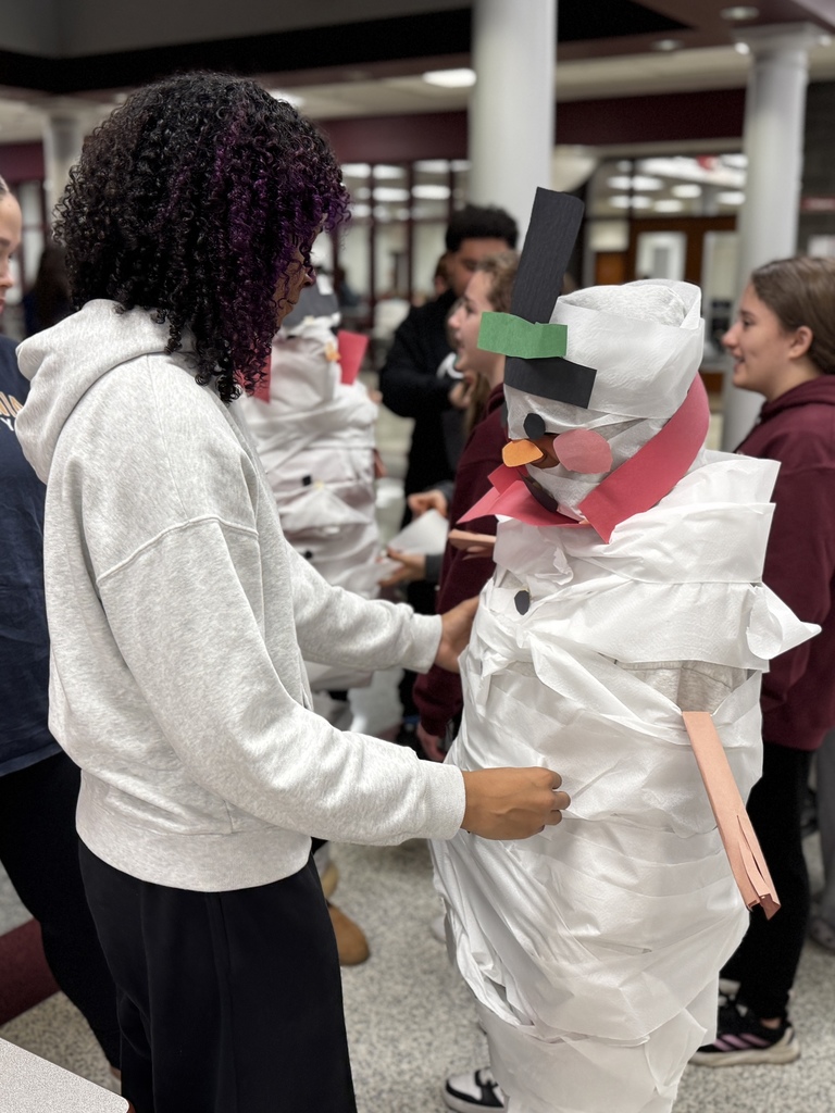 Students wrapping a classmate in toilet paper for a Build A Snowman STEM challenge.