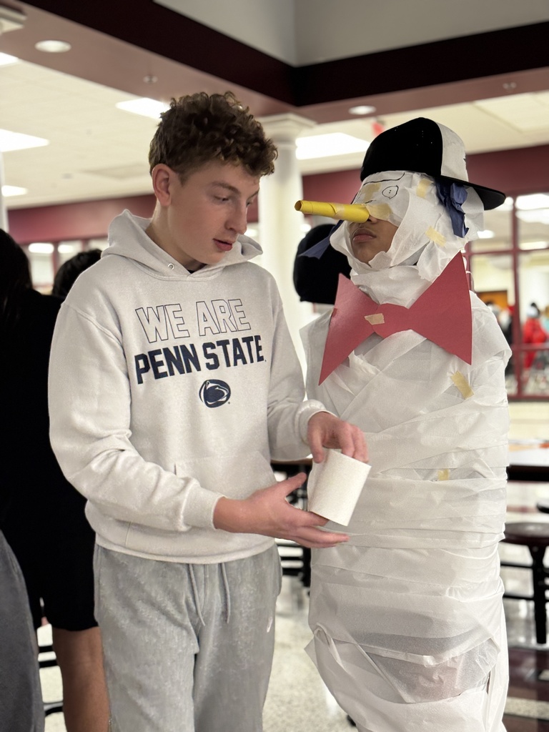 Students wrapping a classmate in toilet paper for a Build A Snowman STEM challenge.