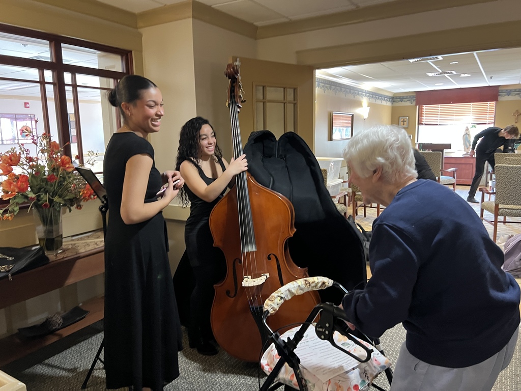 Student musicians interact with a resident of a senior living community.