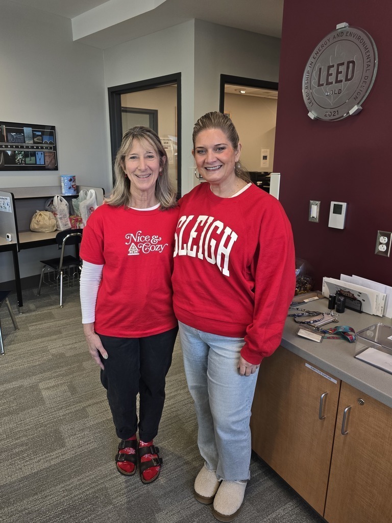 Two staff in red holiday sweatshirts.