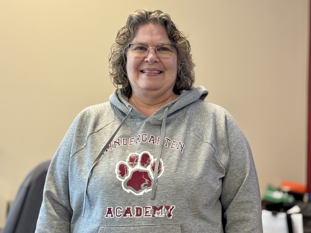 A lady wearing a gray sweatshirt at a desk.