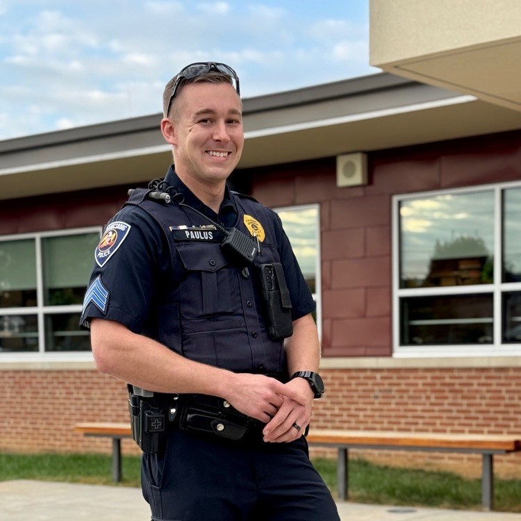 A police officer stands in front of a school.
