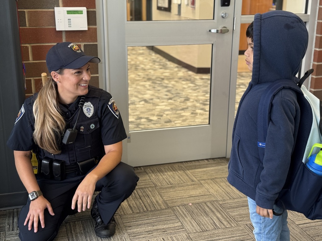 A police officer greets a student as he's coming into school.