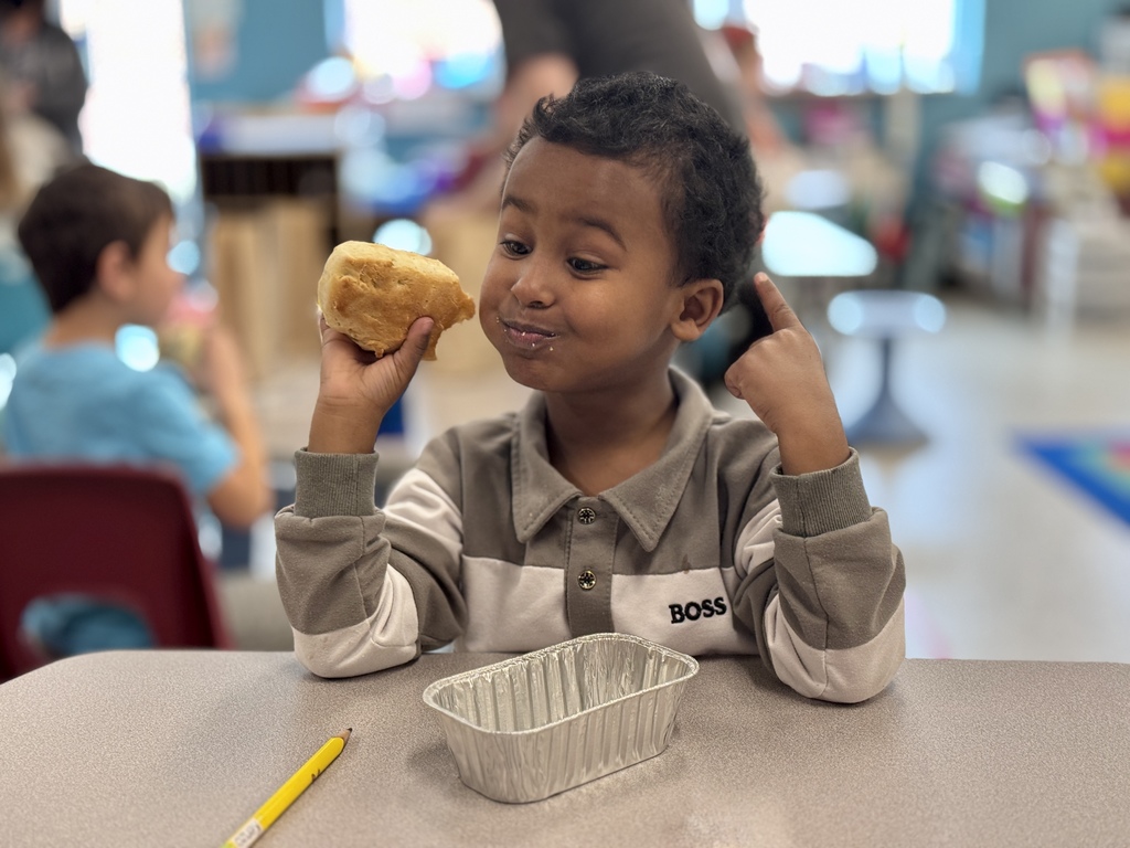 A young student excitedly enjoys a bite of homemade bread.
