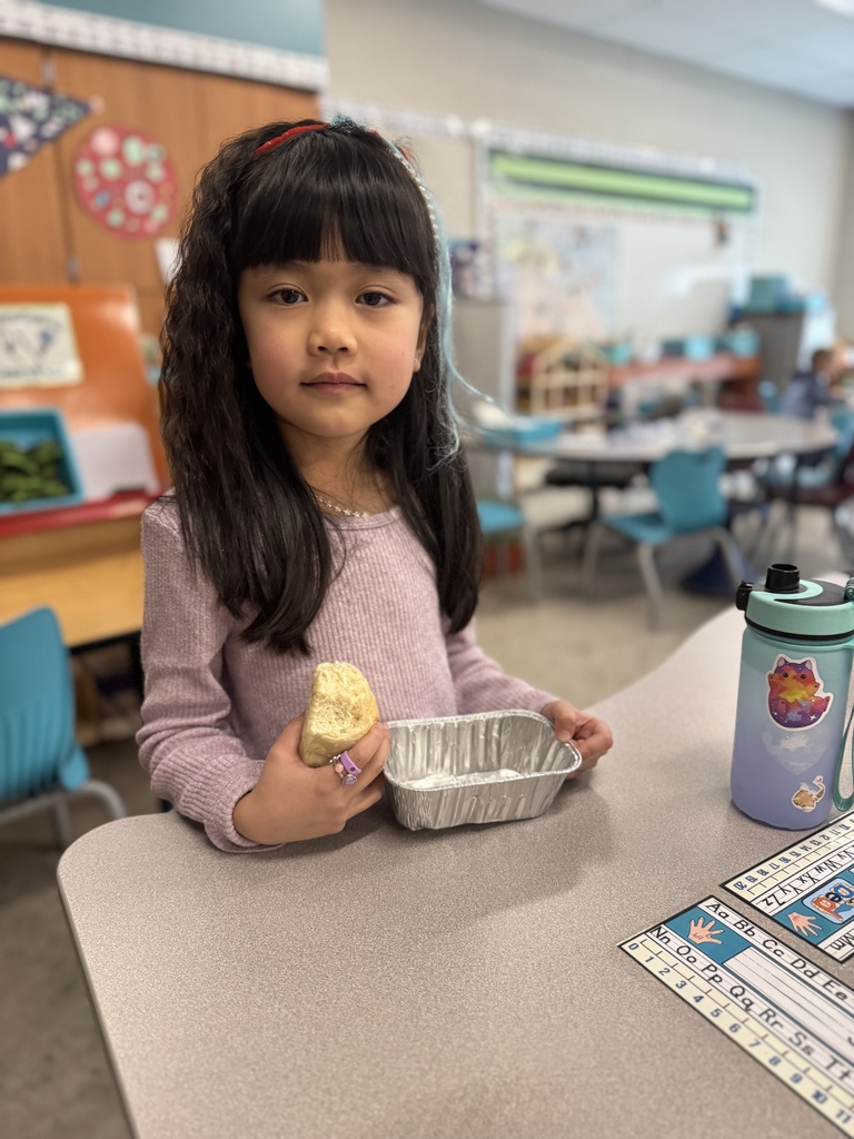 A young student proudly shows her loaf of homemade bread.