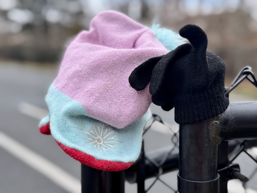 A hat and glove hanging on a playground fence.