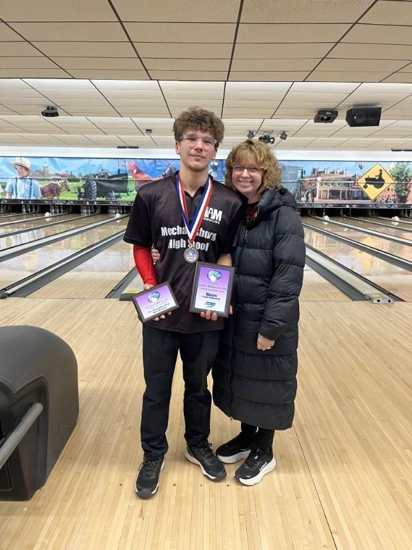 Bowler at bowling alley showing off championship medals.