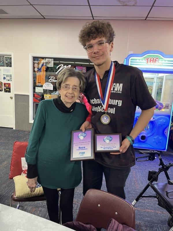 Bowler at bowling alley showing off championship medals.