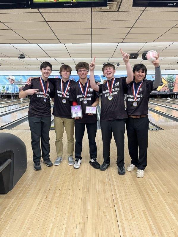 Bowling team at bowling alley showing off championship medals.
