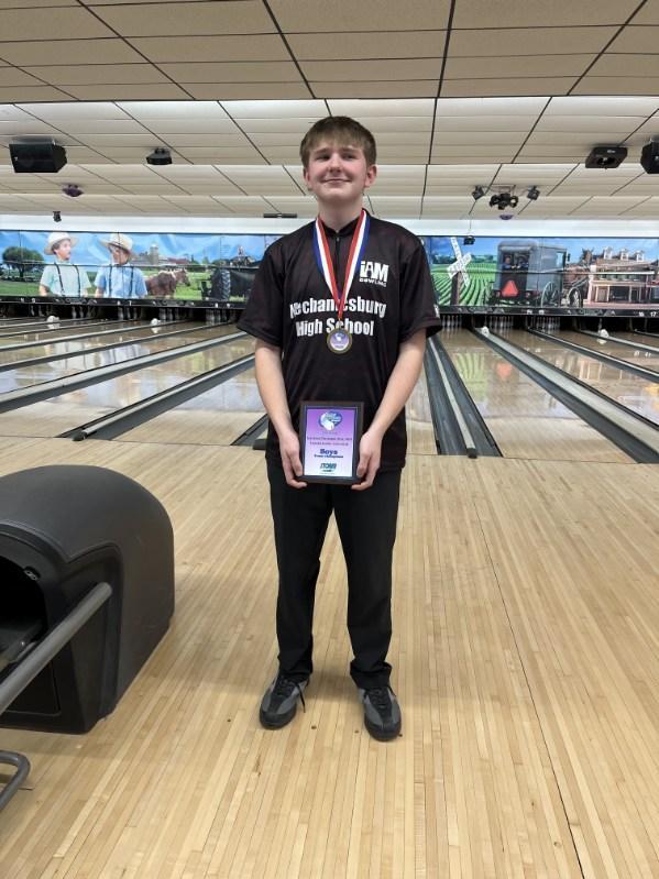 Bowler at bowling alley showing off championship medals.