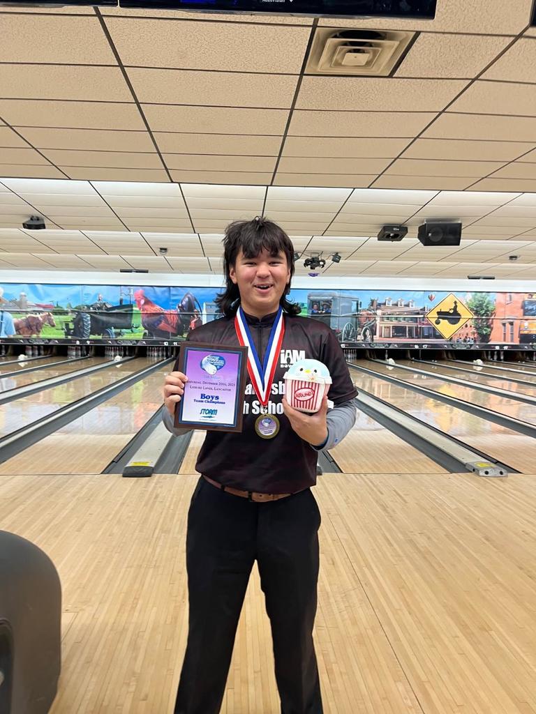 Bowler at bowling alley showing off championship medals.
