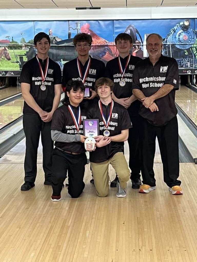 Bowling team at bowling alley showing off championship medals.