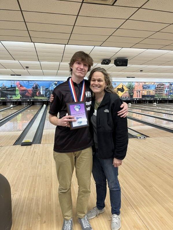 Bowler at bowling alley showing off championship medals.