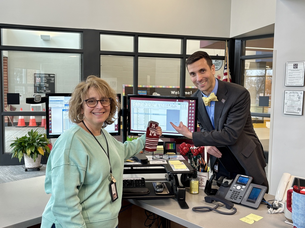 A photo of a man pointing to a computer screen while a lady holds a pair of branded socks.