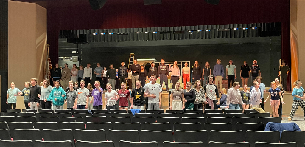 A group of students practicing an on stage musical.