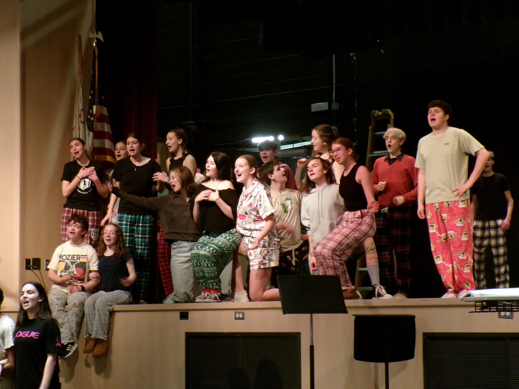 A group of students practicing an on stage musical.
