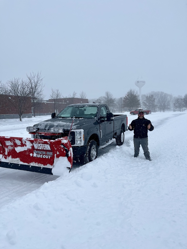 Maintenance crews plow snow outside of a school.
