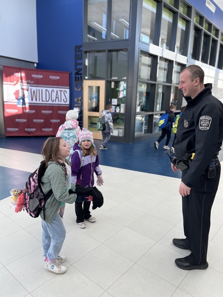 Students welcomed back to school by a police officer.