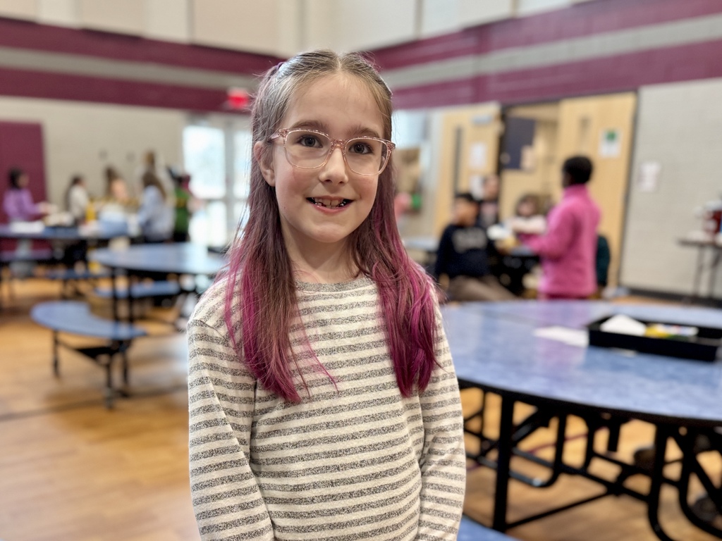 A young student smiles in the school cafeteria.