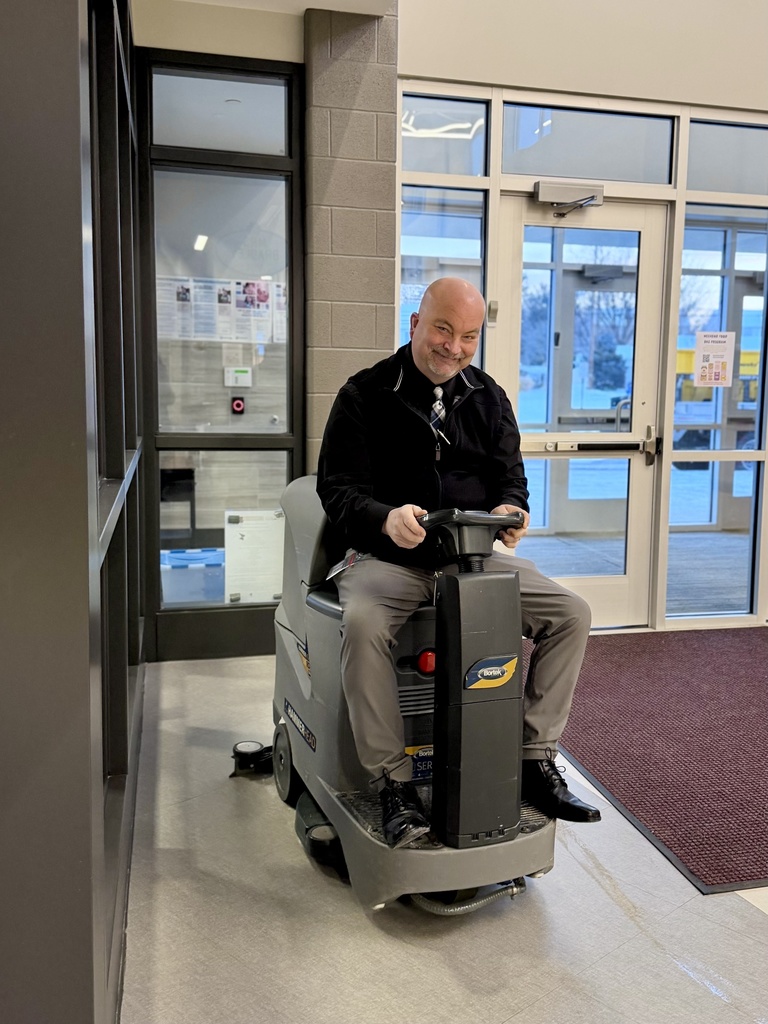 A man in a tie on a Riding Auto Scrubber.