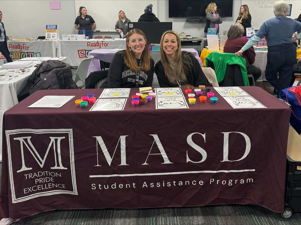 Two staff members sitting at a table with a maroon MASD table cloth.