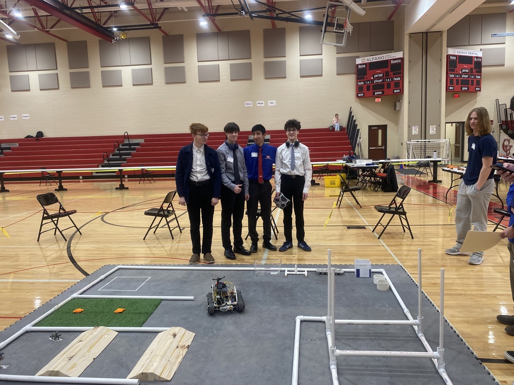 Students standing in front of a robot that they programmed.