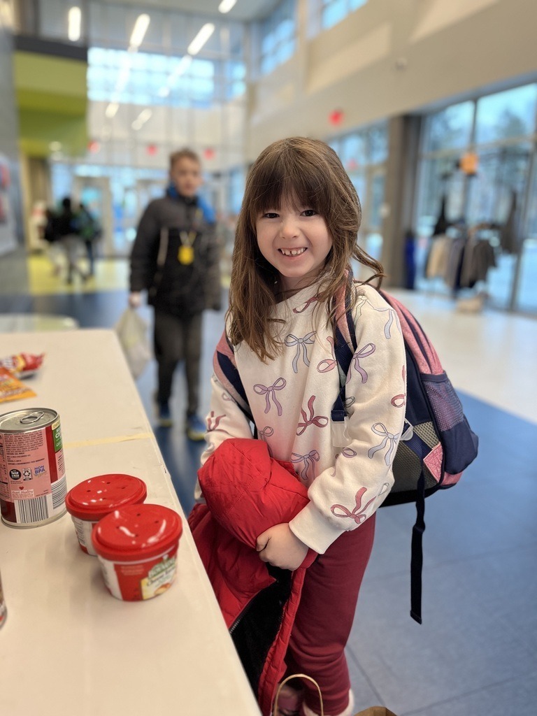 A young student puts a food donation on a table.