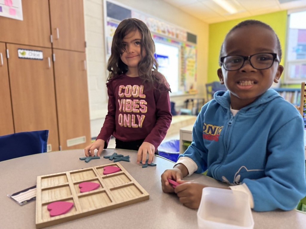Young students play valentines tic tac toe together.