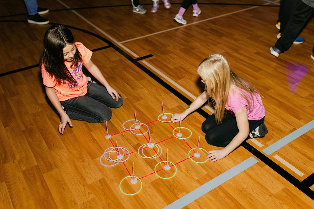 Two students sit on a floor to play a game with rings.