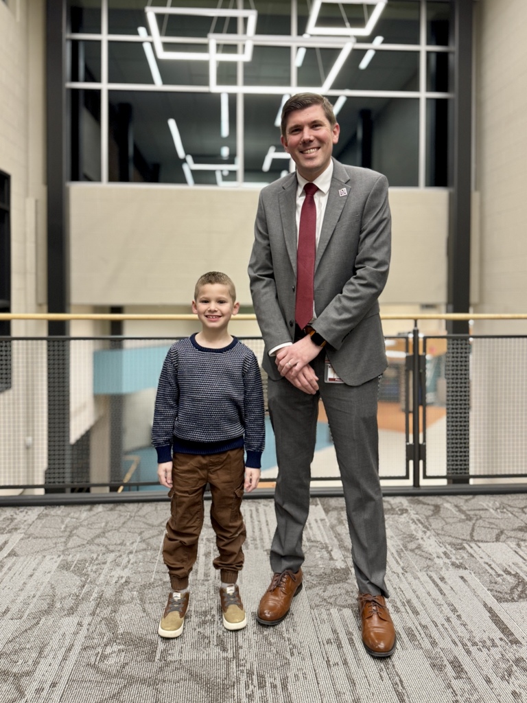 A young student standing next to his principal.