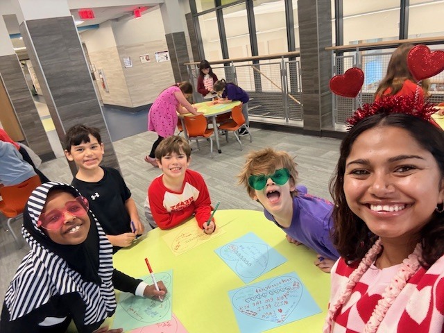 A teacher with students at a table during valentine's day.