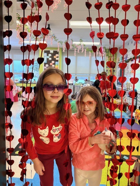 Students walking out of a door lined with red hearts.
