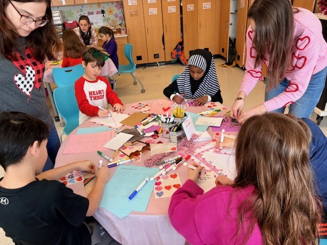 Students at a table working on a valentine's craft.
