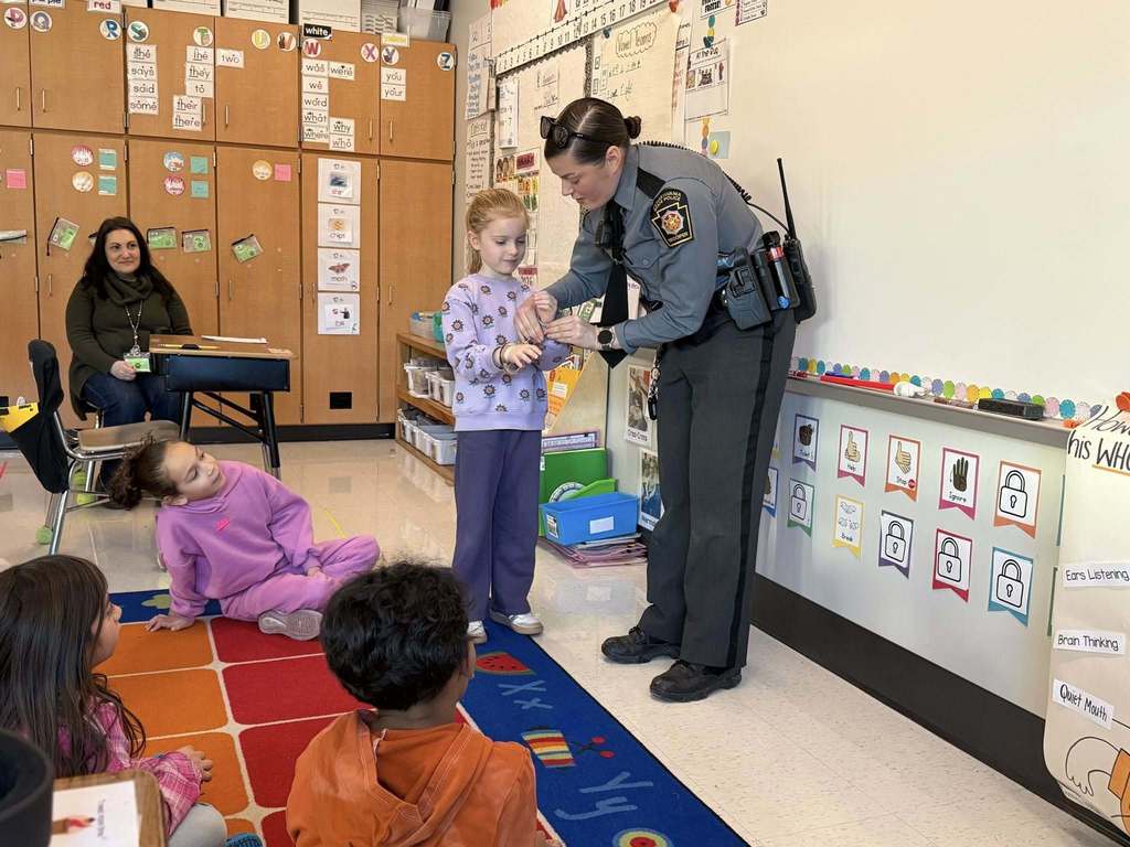 A friendly state police trooper demonstrates how handcuffs work for a group of young students.