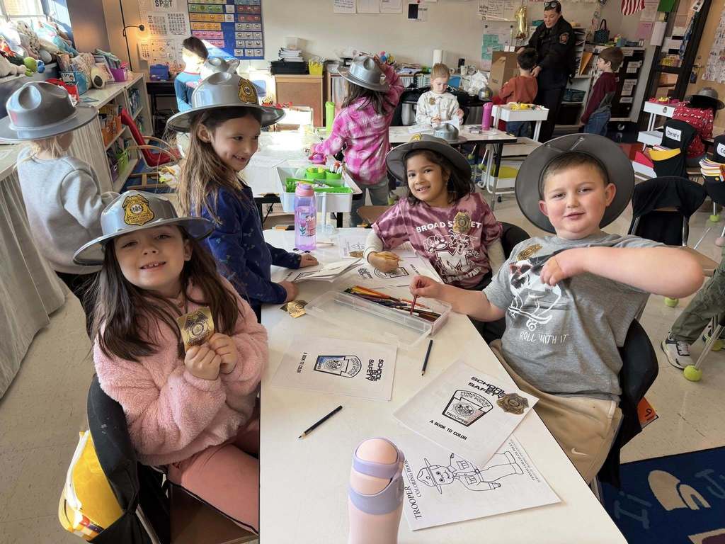 Young students wear pretend state police trooper hats.