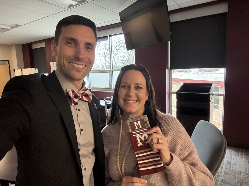 A man presents a woman with a pair of maroon branded socks.