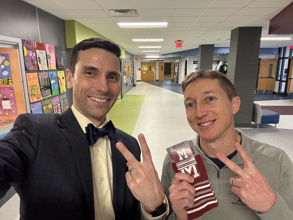 Two men standing side by side holding up two fingers (for the number 2) and a pair of socks.