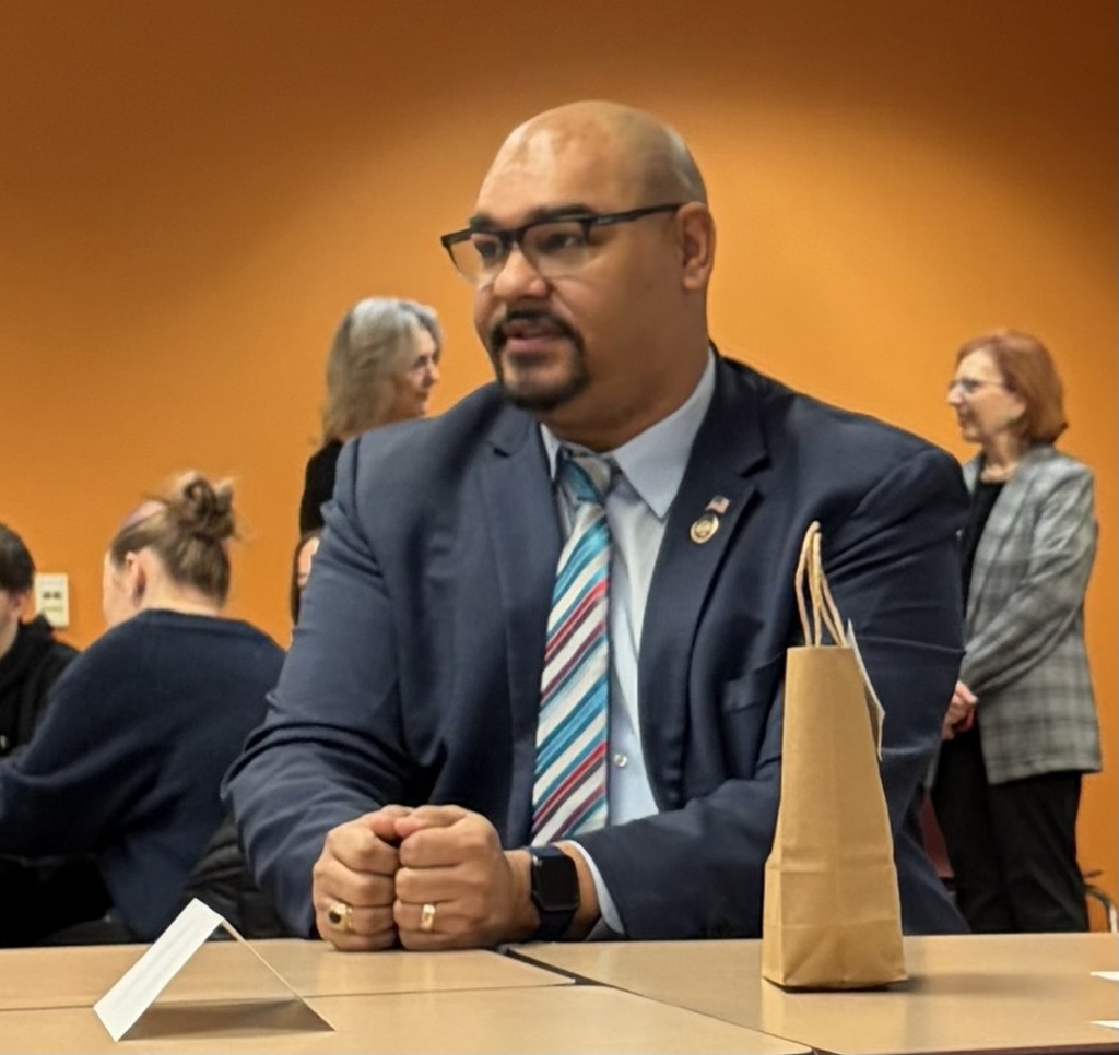 A gentleman in a suit talking with students.