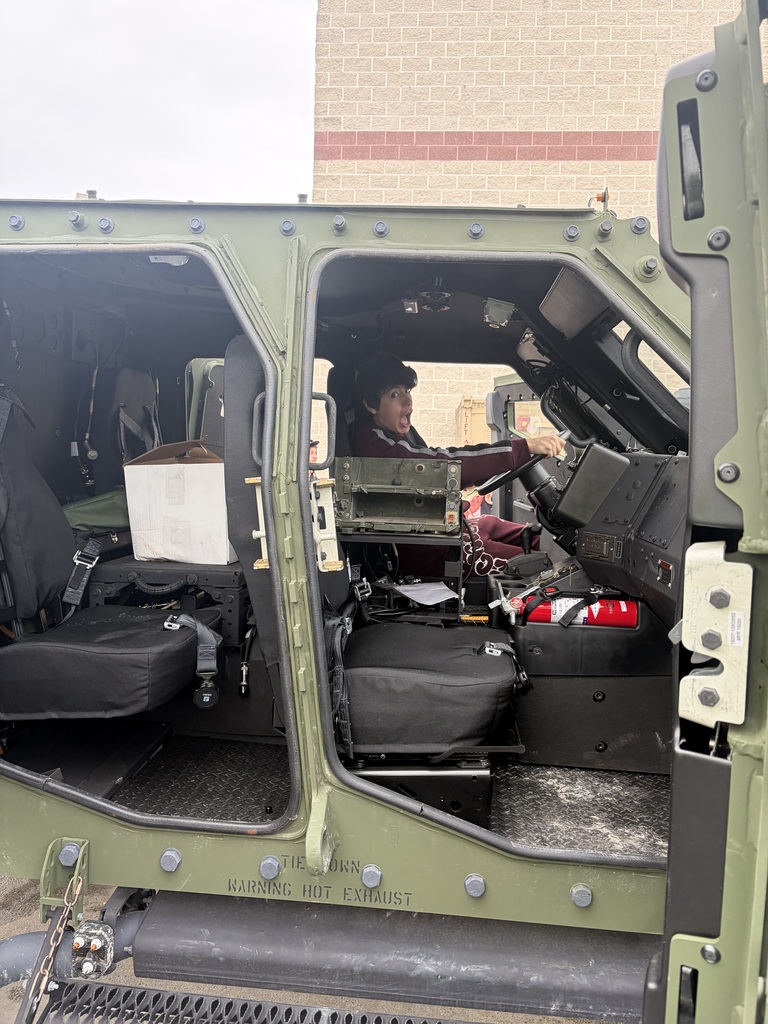 A student behind the wheel of a military vehicle.