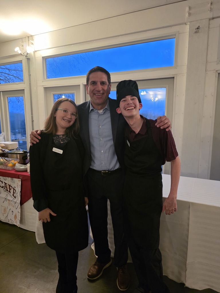Two students stand alongside their principal at a special community event.